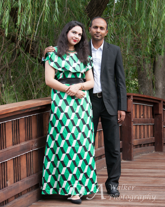 Indian couple standing on footbridge with tree in background.